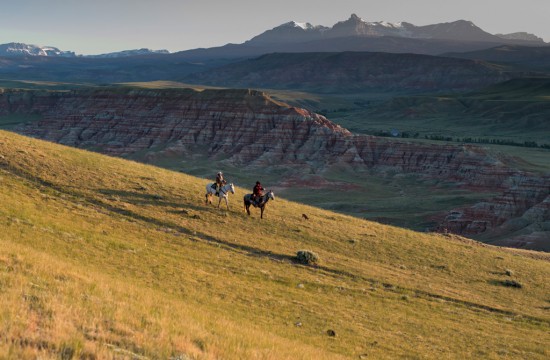 Two riders on horseback in an expansive landscape at sunset at CM Ranch in Dubois, WY | cabins in Dubois Wyoming